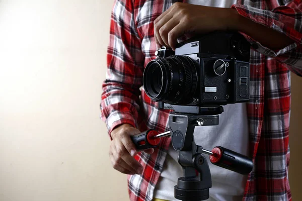 Ενηλίκων κρατώντας μια παλιά και vintage μεσαίου μεγέθους κάμερα φιλμ σε ένα τρίποδο. — Φωτογραφία Αρχείου