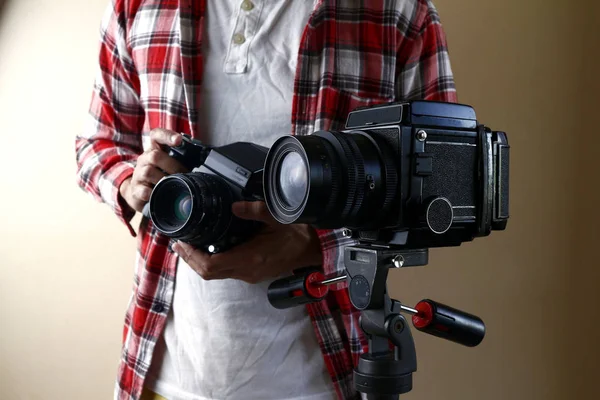 Hombre adulto sosteniendo una vieja y vintage cámara de película de formato medio en un trípode . —  Fotos de Stock