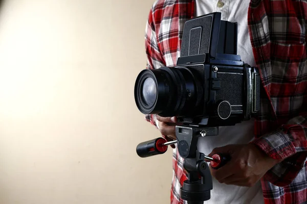 Adult man holding an old and vintage medium format film camera on a tripod. — Stock Photo, Image