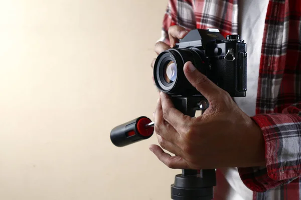 Adult man holding an old and vintage small format or 135mm film camera on a tripod — Stock Photo, Image