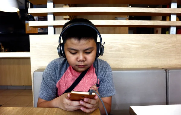 Young Asian boy using a smartphone and headphone — ストック写真