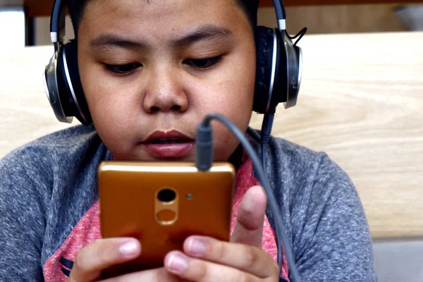 Tineri băiat asiatic folosind un smartphone și căști — Fotografie, imagine de stoc
