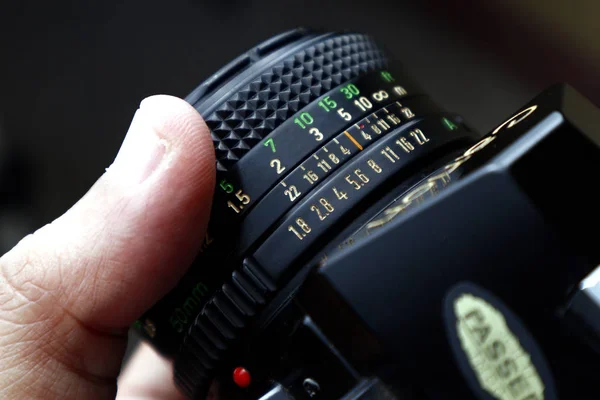 Mão segurando o anel de focagem na lente de uma câmera de filme de 35mm antiga e vintage — Fotografia de Stock