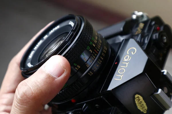 Mão segurando o anel de focagem na lente de uma câmera de filme de 35mm antiga e vintage — Fotografia de Stock