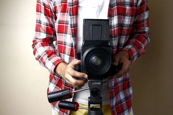 Vuxen man som håller en gammal och vintage medium format filmkamera på ett stativ. — Stockfoto