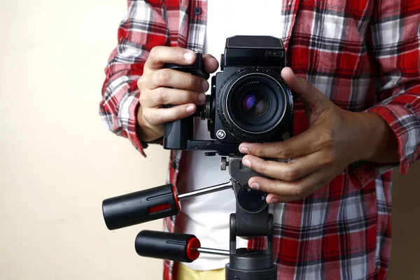 Дорослий чоловік тримає стару і старовинну камеру середнього формату на тринозі . — стокове фото