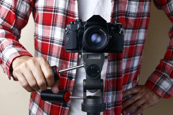 Hombre adulto sosteniendo una vieja y vintage de pequeño formato o 135mm cámara de película en un trípode —  Fotos de Stock