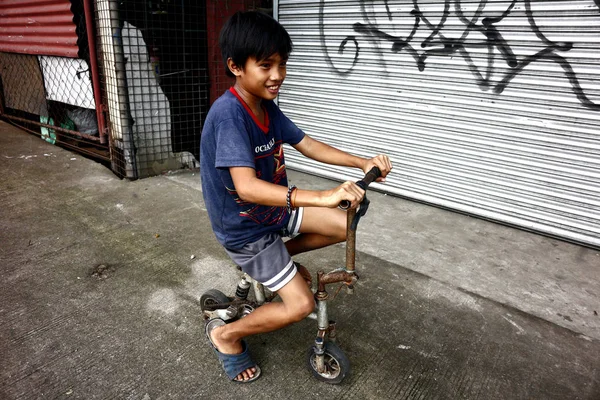 Jovem ásia menino passeio um pequeno improvisado bicicleta feito de reciclado lixo materiais . — Fotografia de Stock