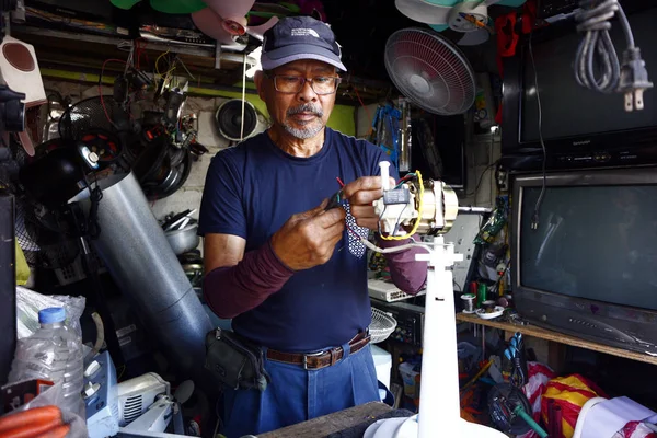 Ev aletleri tamircisi tamir atölyesindeki eski bir vantilatörü tamir ediyor..