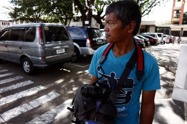 Bir fotoğrafçı, bahçe parkında fotoğraf çektirmek isteyen turistlere bakar.