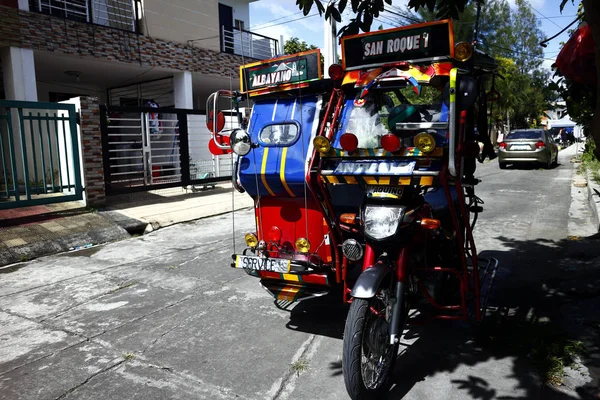 Triciclo de passageiros decorado e colorido estacionado sob a sombra de uma árvore por uma calçada . — Fotografia de Stock
