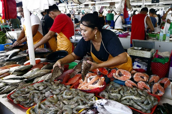 Vendedores em um mercado público molhado vendem peixe e outros frutos do mar aos clientes . — Fotografia de Stock