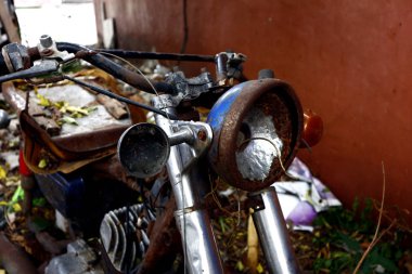 Eski, kırık ve paslı motosiklet boş bir arazide.