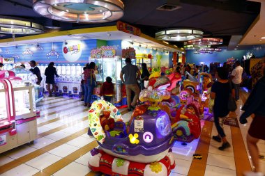 Müşteriler, bir alışveriş merkezinin içindeki oyun salonu içinde oyunlardan, gezintilerden ve diğer eğlencelerden hoşlanırlar..