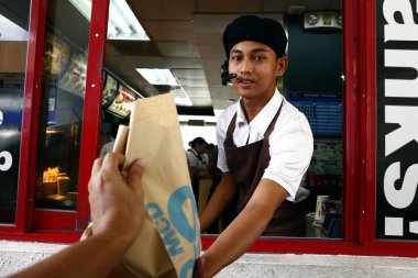 Fast food restoranındaki işçiler vitrinden müşterinin yemek siparişini verir.