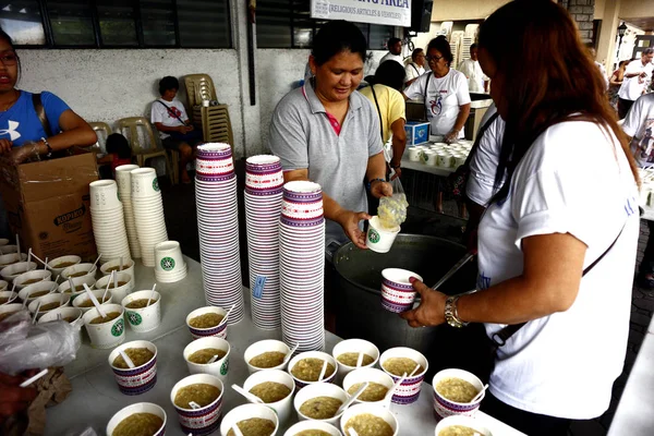 Voluntarios de una organización sin fines de lucro sirven comida al público durante un programa de alimentación semanal — Foto de Stock