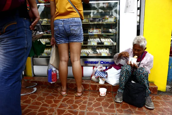 La anciana filipina se sienta en una acera y ruega a la gente que le dé comida o limosna — Foto de Stock
