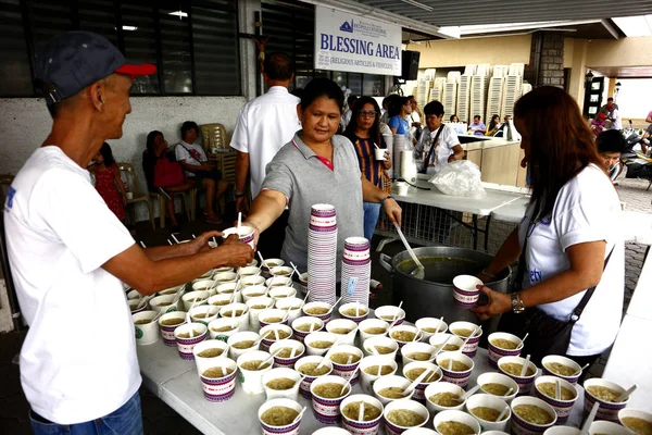 Voluntarios de una organización sin fines de lucro sirven comida al público durante un programa de alimentación semanal — Foto de Stock