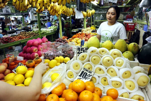 Propietario del puesto de mercado vende frutas frescas en un mercado público . — Foto de Stock