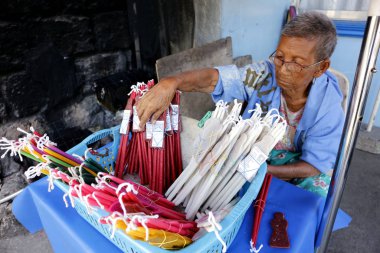 Sokak satıcısı, Antipolo Katedrali 'nin dışındaki derme çatma tezgahında mum satıyor.
