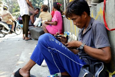 Bir sokak satıcısı her türlü eski ve kullanılmış ev eşyalarını satar ve kaldırımda eski bir çalar saati tamir eder.