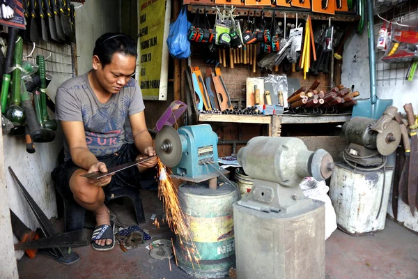 Bir teneke parçası, müşterisi için testereyi keskinleştirir.