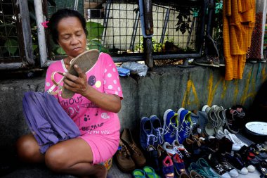 Bir sokak satıcısı kaldırımda her türlü eski ve kullanılmış ayakkabı ve giysi satar.