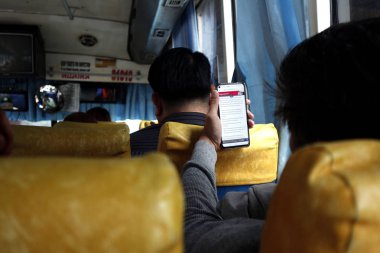 Yolcu, yolcu otobüsünde zaman geçirmek için akıllı telefonunu kullanıyor.