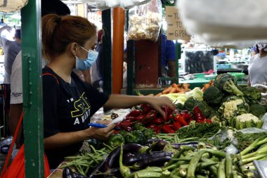 Antipolo Şehri, Filipinler - 20 Mart 2020: Filipinli kadın Covid 19 virüs salgını sırasında marketten yiyecek alırken cerrahi maske takıyor.