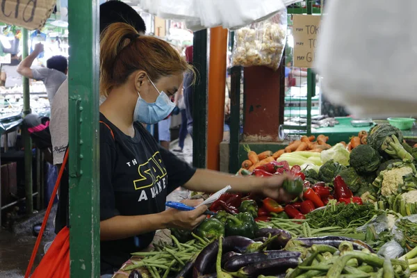 Antipolo Şehri, Filipinler - 20 Mart 2020: Filipinli kadın Covid 19 virüs salgını sırasında marketten yiyecek alırken cerrahi maske takıyor.