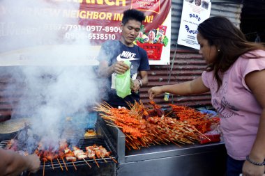 Antipolo, Rizal, Filipinler - 20 Mart 2020: Yemek tezgahındaki sokak yemeği satıcısı barbekü çubuklarında ızgara domuz eti ve tavuk bağırsağı satıyor.