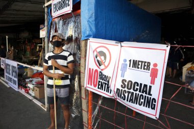 Antipolo Şehri, Filipinler - 31 Mart 2020: Bir gönüllü, Covid 19 virüs salgını sırasında yüzünüze alkol püskürtmek ve yüzünüze maske takmak için bir kamu pazarının girişinde nöbet tutuyor.