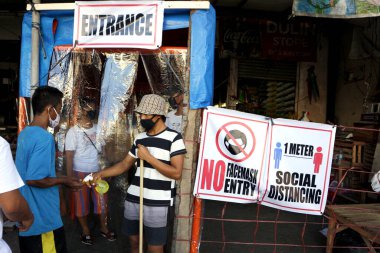 Antipolo Şehri, Filipinler - 31 Mart 2020: Bir gönüllü, Covid 19 virüs salgını sırasında yüzünüze alkol püskürtmek ve yüzünüze maske takmak için bir kamu pazarının girişinde nöbet tutuyor.