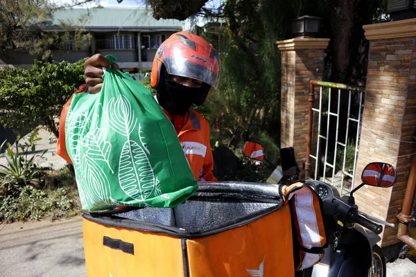 Antipolo Şehri, Filipinler - 2 Nisan 2020: Bir kurye, Covid 19 virüs salgını nedeniyle karantina ya da toplum karantinası sırasında müşteriye teslim edilecek bakkal malzemeleri yükler.