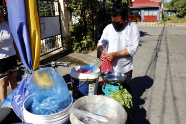 Antipolo Şehri, Filipinler - 3 Nisan 2020: Satıcı, müşteriler Covid 19 virüs salgını nedeniyle evlerini terk etmesinler diye halka balık satıyor.
