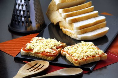 Peynirden, biberden ve domates sosundan yapılmış pizza soslu dilimlenmiş ekmeğin fotoğrafı..