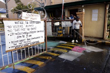Antipolo Şehri, Filipinler - 22 Nisan 2020: Covid 19 virüs salgını sırasında ayak ve araç lastiklerini dezenfekte etmek için giriş kapısına dezenfekte çözümüyle köy güvenliği su döktü.