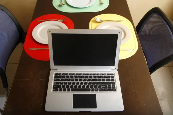 Foto Computadora Portátil Platos Utensilios Una Mesa Comedor — Foto de Stock