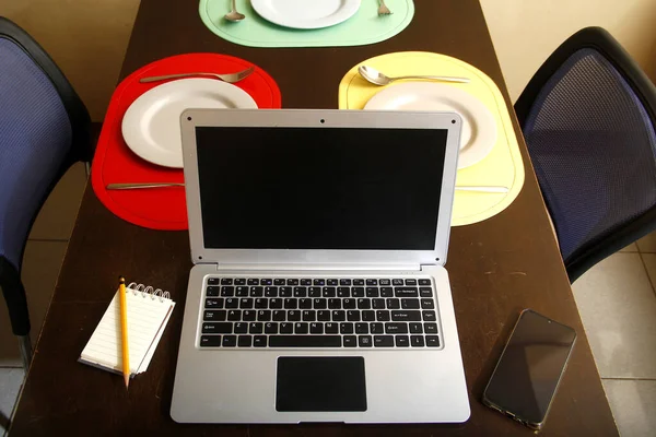 ダイニングテーブルのラップトップコンピュータ スマートフォン ノートブック プレートや道具の写真 — ストック写真