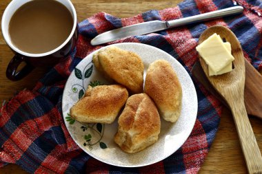 Pan de sal ya da Tuz Ekmeği olarak adlandırılan taze fırınlanmış Filipin ekmeği, bir masanın üzerinde kahve ve peynir dilimleri Pan de sal veya Tuz Ekmeği adlı taze fırınlanmış Filipinli ekmeğin fotoğrafı, kahve ve peynir dilimleri..