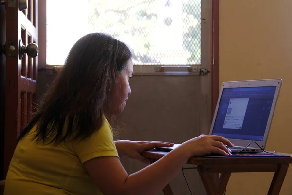 自宅のリビングルームでコンピュータを操作しているアジア人女性の写真 — ストック写真