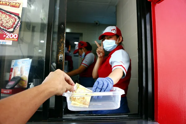 Antipolo Şehri, Filipinler - 5 Mayıs 2020: Bir fast food restoranının çalışanı, Covid 19 virüs salgını sırasında vitrindeki bir müşteriden ödeme aldı.