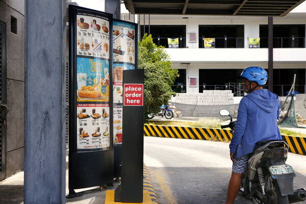 Antipolo City, Philippines - May 5, 2020: Customers in their cars and motorcycles line up at the drive thru facility of a fast food restaurant during the Covid 19 virus outbreak.