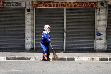 Antipolo Şehri, Filipinler - 7 Mayıs 2020: Covid 19 virüs salgını nedeniyle kapatma sırasında sokak temizleyicisi kapalı ticari işletmelerin önünde temizlik yapıyor.