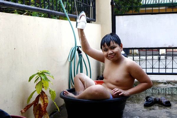 夏の暑さに勝つために仮設シャワーとしての水盤と水のホースで冷却若いアジアの少年の写真 — ストック写真