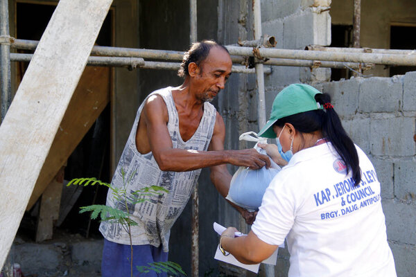 Antipolo City, Philippines - May 11, 2020: Local government workers and members of the national police distribute relief goods to residents during the lockdown due to Covid 19 virus outbreak.