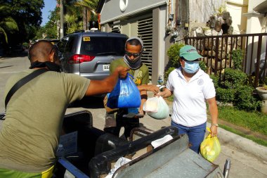 Antipolo City, Philippines - May 11, 2020: Local government workers and members of the national police distribute relief goods to residents during the lockdown due to Covid 19 virus outbreak. clipart