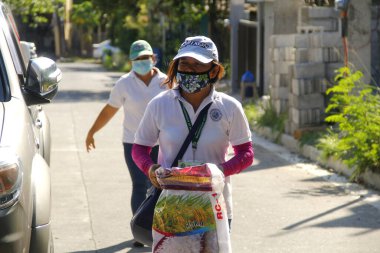 Antipolo Şehri, Filipinler - 11 Mayıs 2020: Yerel hükümet çalışanları ve ulusal polis memurları, Covid 19 virüs salgını nedeniyle tecrit sırasındaki sakinlere yardım ürünleri dağıtıyor.