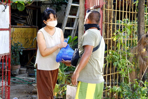 Antipolo City, Philippines - May 11, 2020: Local government workers and members of the national police distribute relief goods to residents during the lockdown due to Covid 19 virus outbreak.