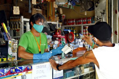 Antipolo Şehri, Filipinler - 16 Mayıs 2020: Mağaza sahibi, Covid 19 virüs salgını sırasında işletmelere izin verildiğinde güvenlik önlemi olarak eldiven, yüz maskesi ve yüz maskesi takıyor.